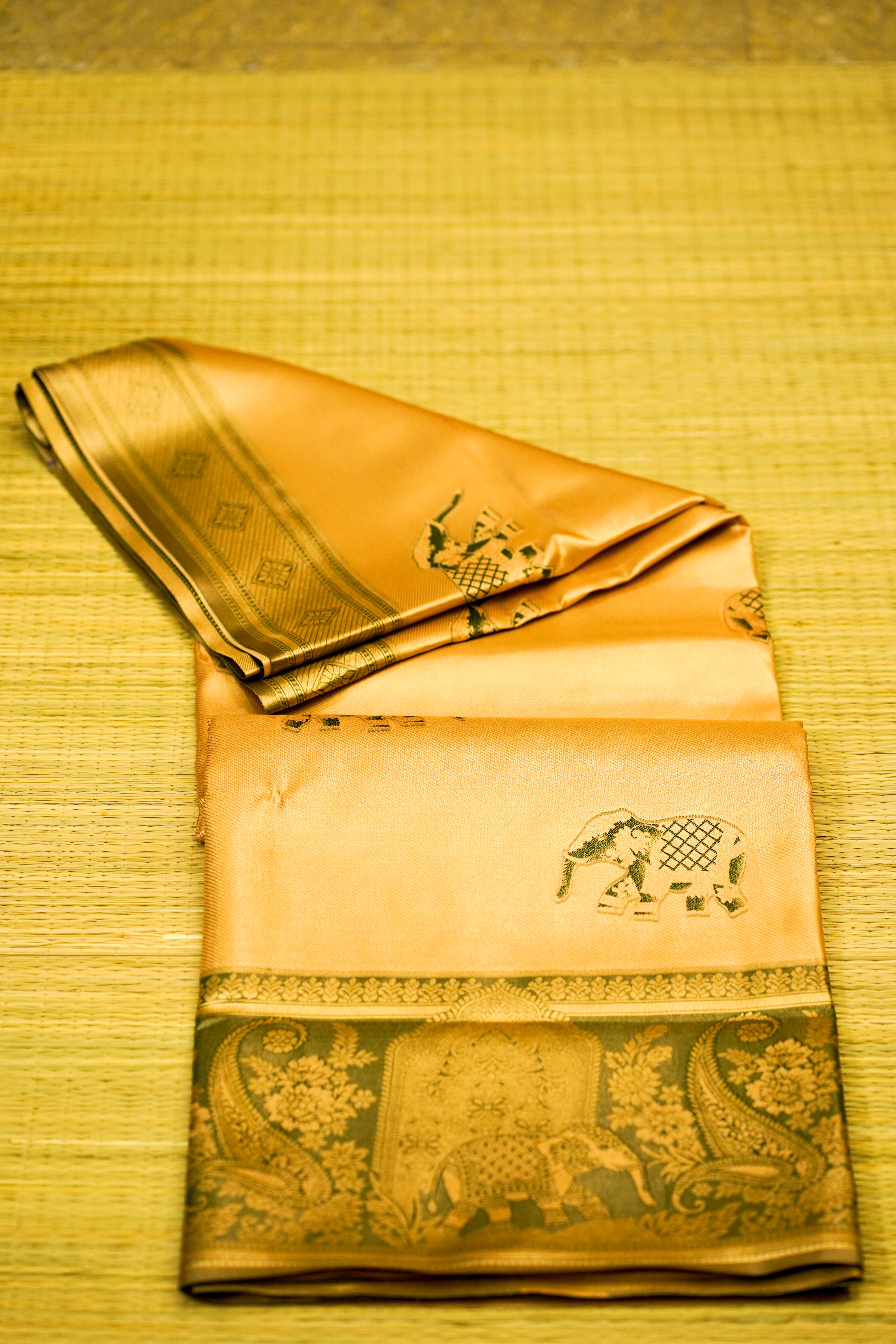 Folded traditional fabric with elephant design on a yellow textured background