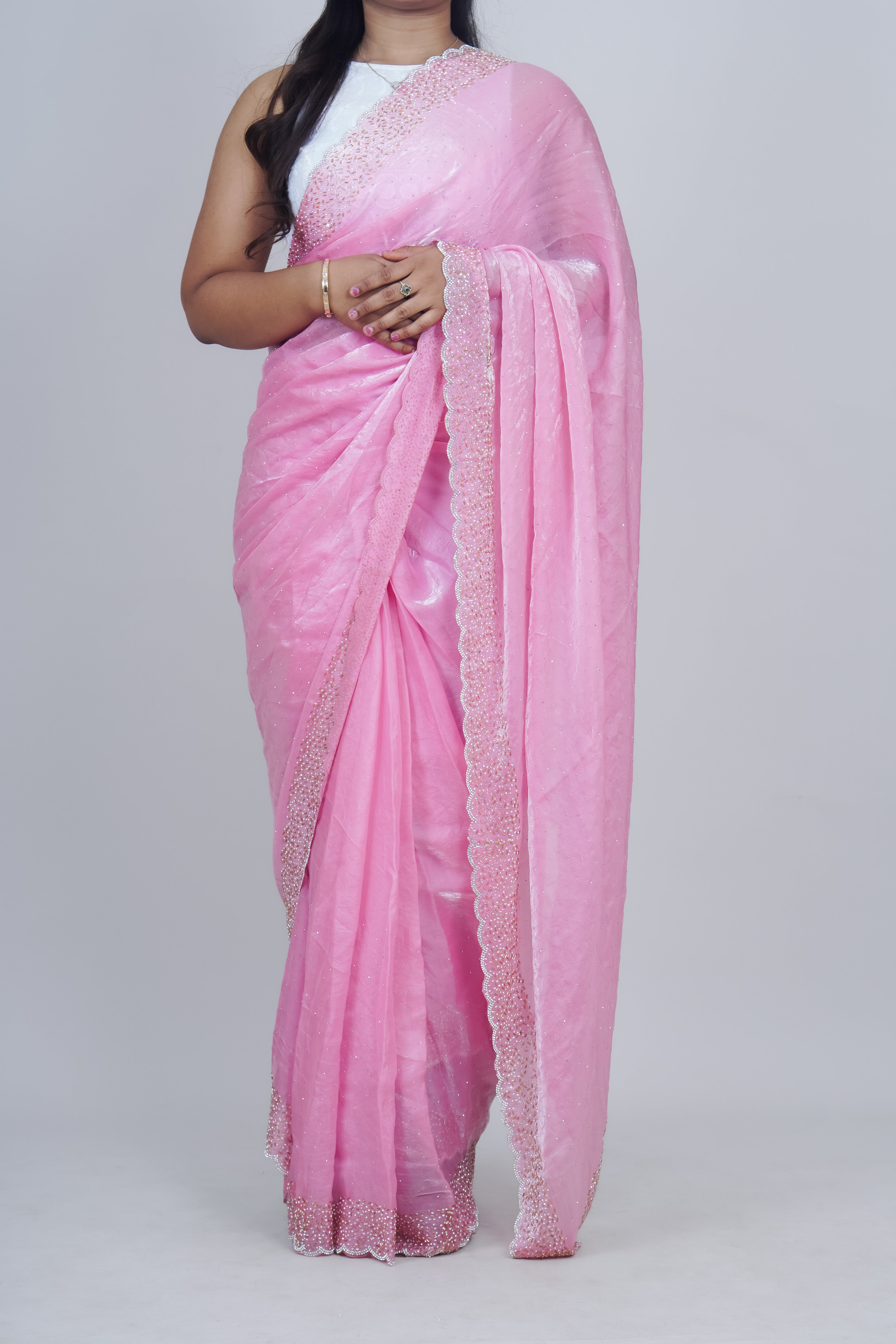 Pink saree with white border on a plain background