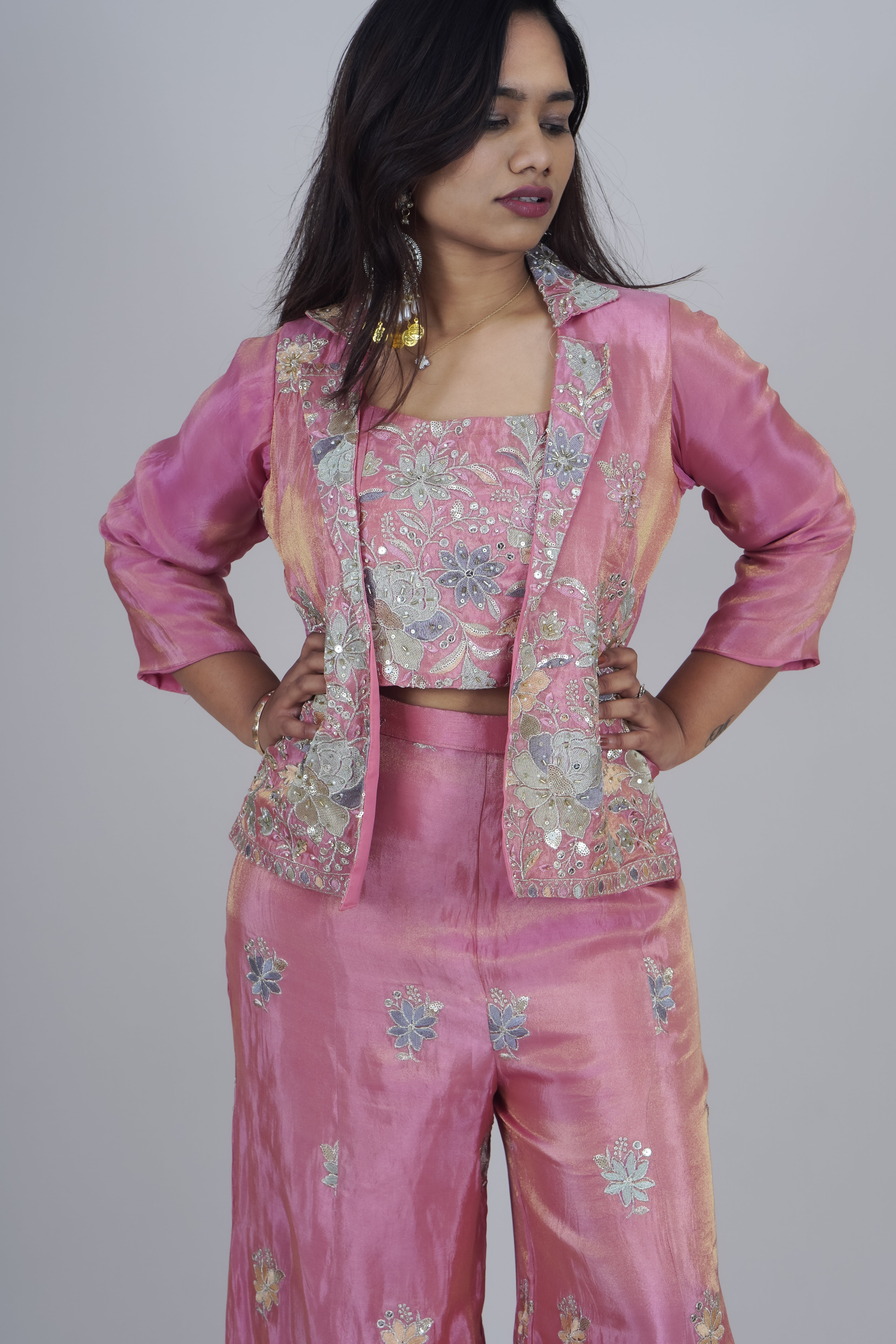 Woman wearing a pink embroidered outfit on a plain background