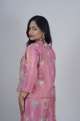 Woman wearing a pink traditional outfit with floral patterns on a plain background