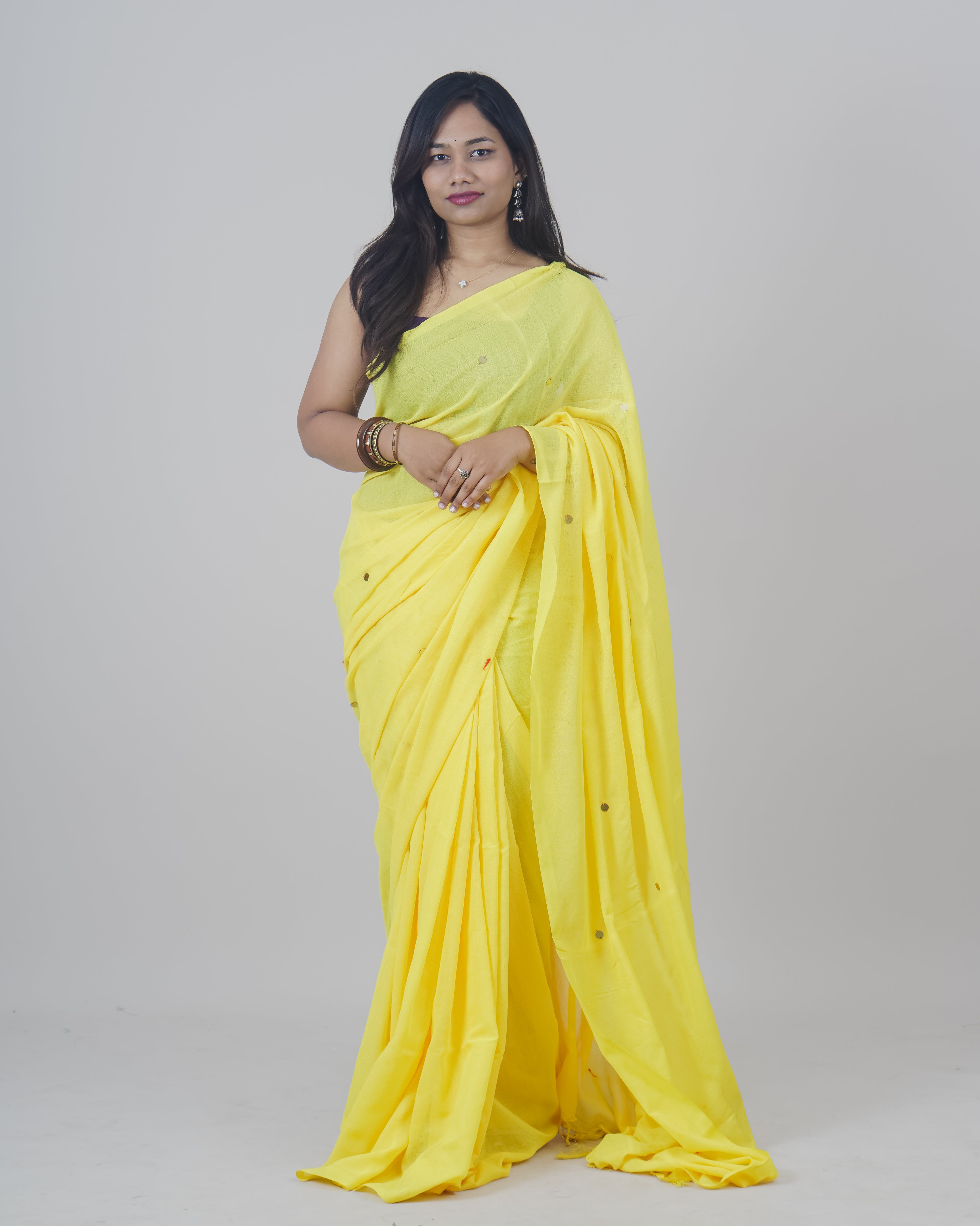 Woman wearing a yellow saree on a gray background