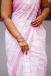 Close-up of a person wearing a pink and white checkered saree with jewelry.
