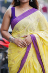 Woman wearing a yellow saree with purple border and jewelry. www.laaki.co