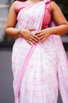 Person wearing a pink and white checkered saree with a blurred background. laaki
