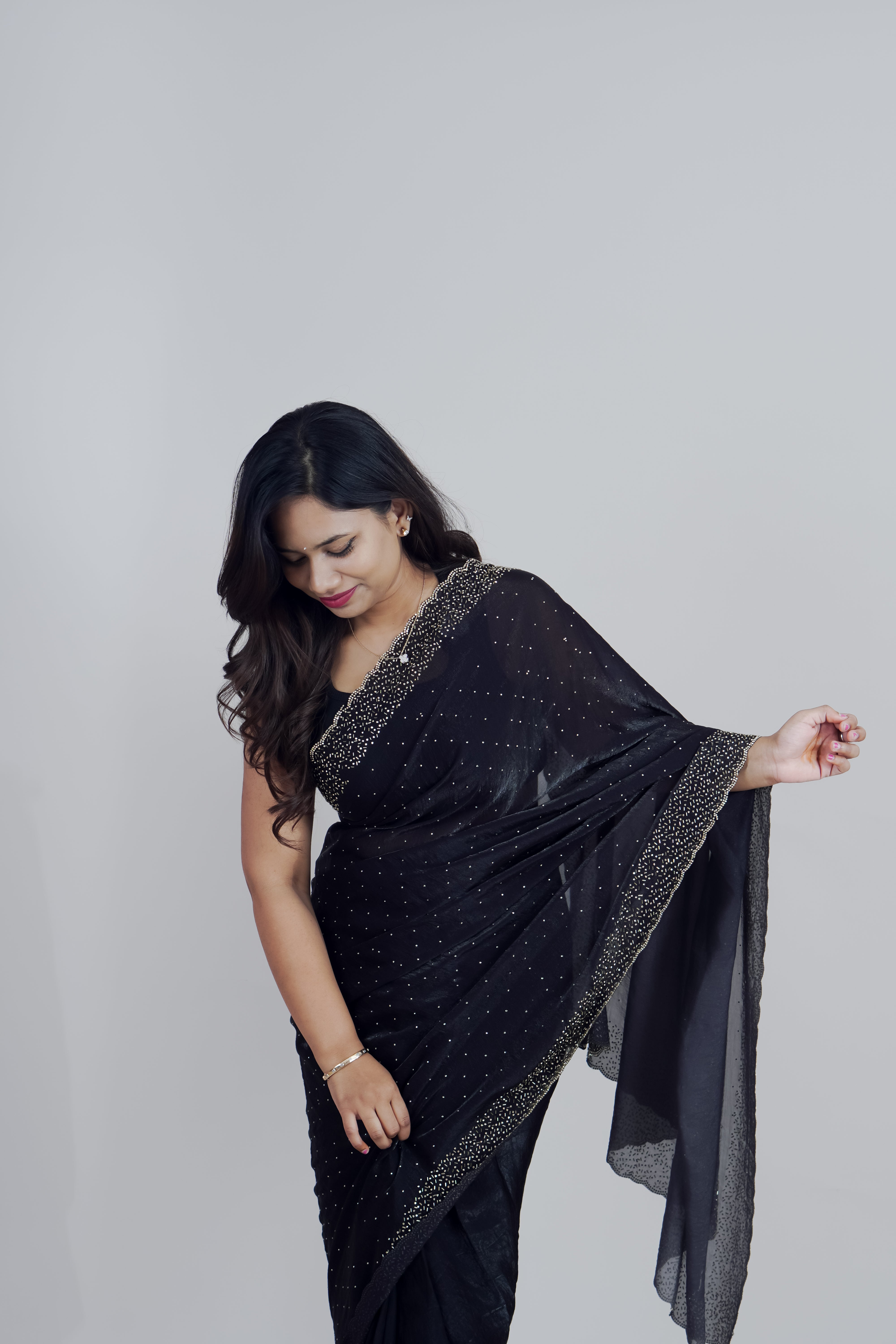 Woman wearing a black saree with gold border against a plain background www.laaki.co