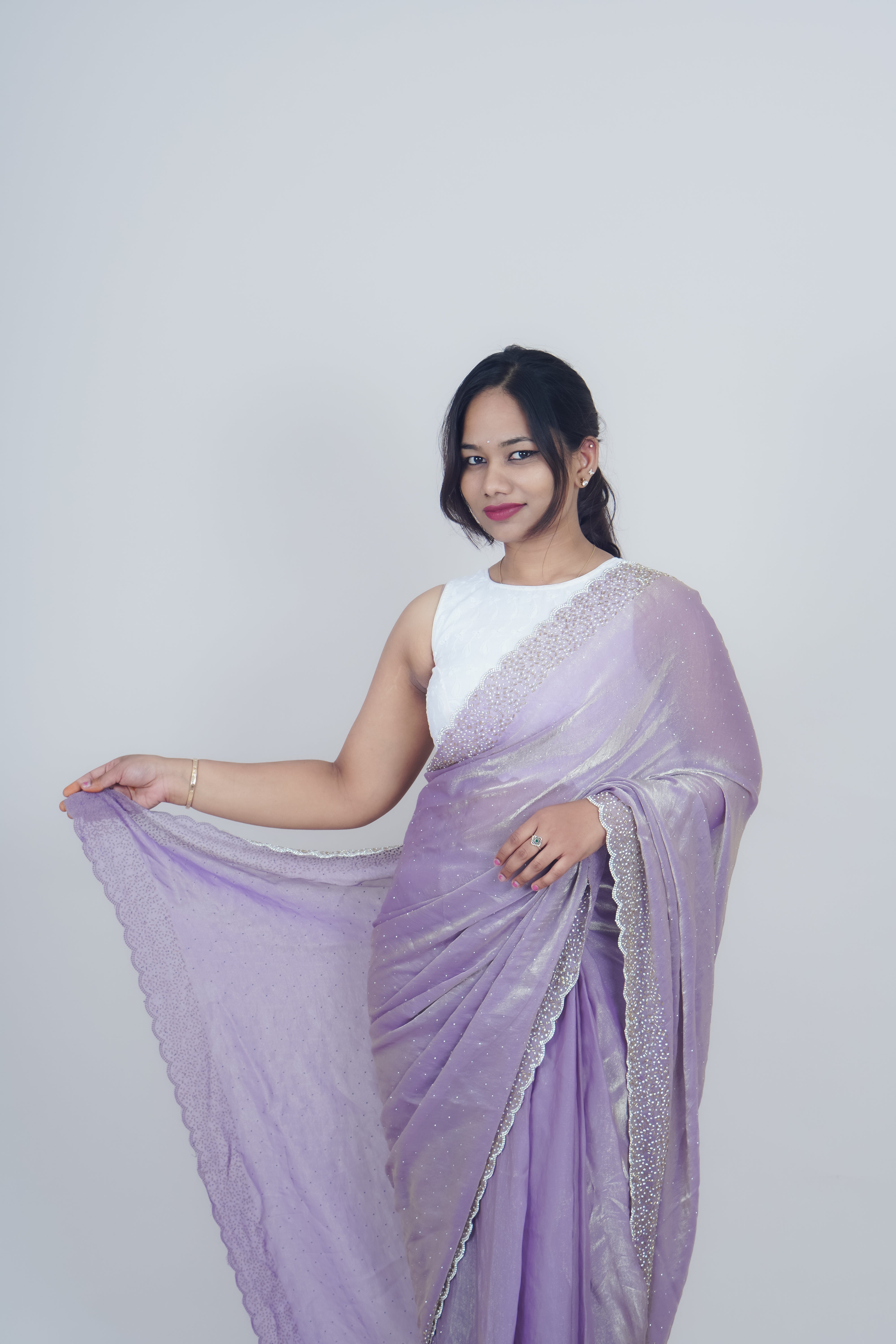 Woman wearing a lavender saree with a white blouse against a plain background www.laaki.co