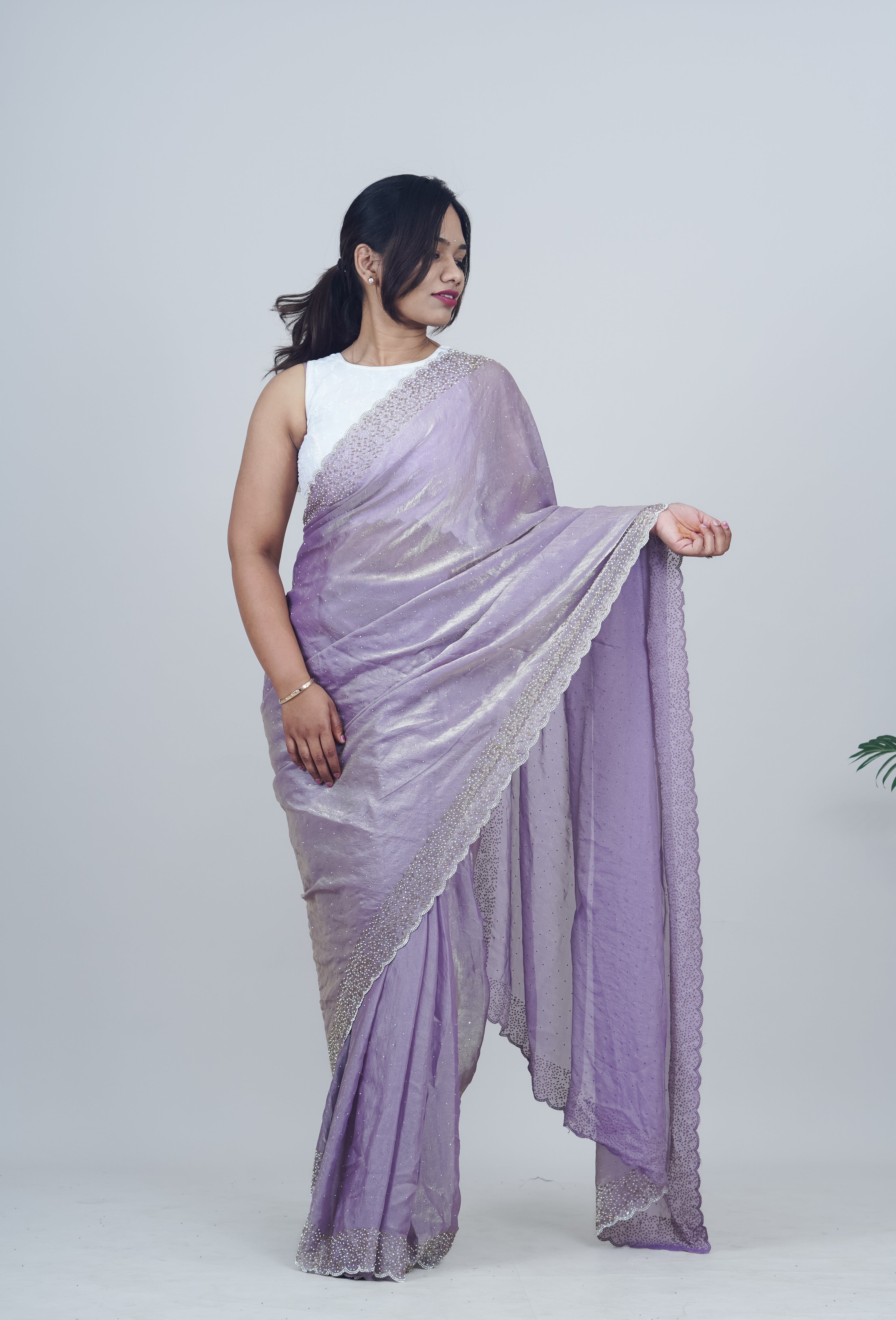 Woman wearing a light purple saree with a white blouse against a plain background www.laaki.co