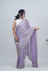 Woman wearing a light purple saree with a white blouse against a plain background www.laaki.co