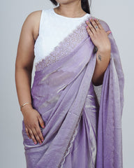 Woman wearing a white top and purple saree with silver border on a plain background www.laaki.co