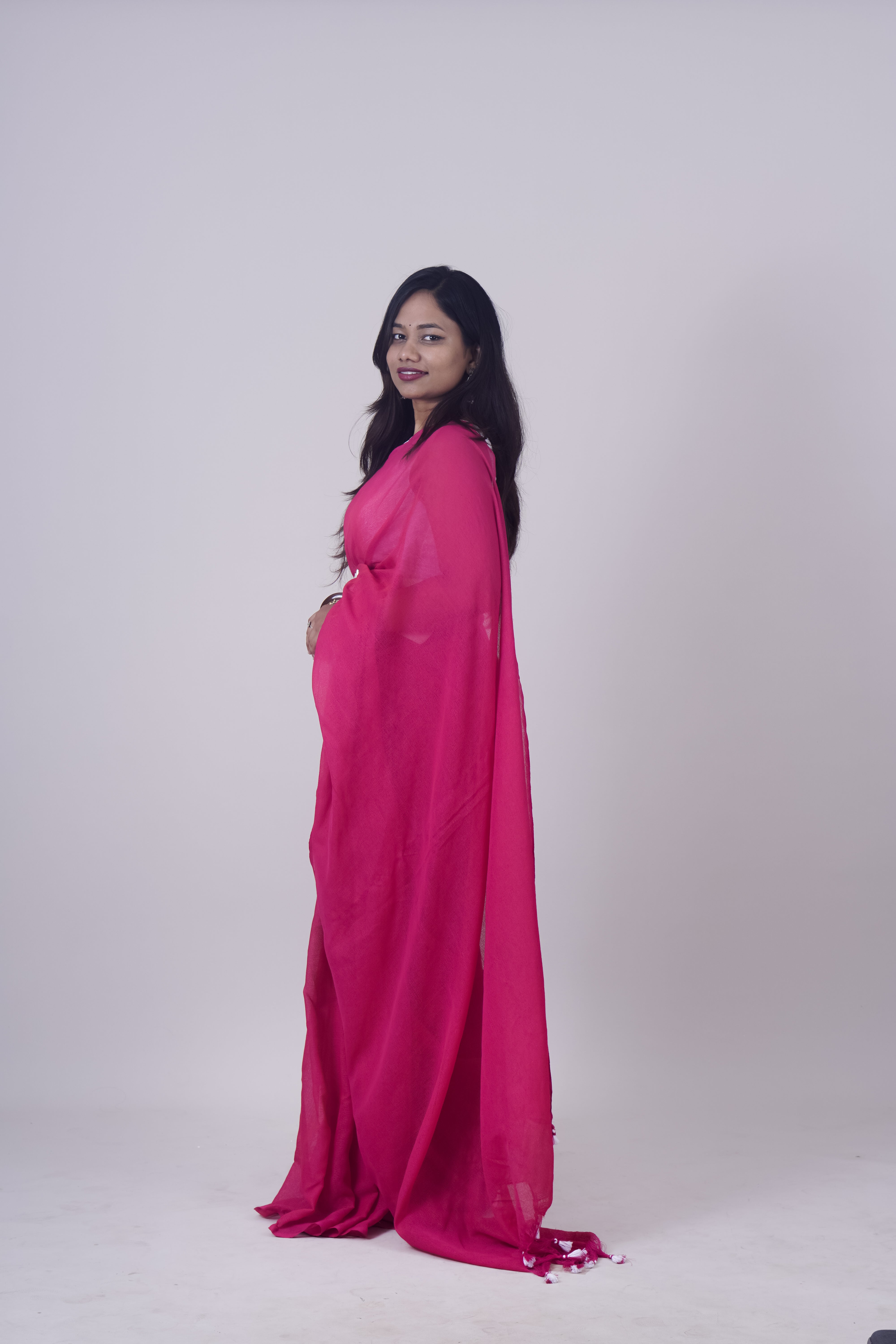 Woman wearing a bright pink saree against a white background