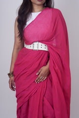 Woman wearing a bright pink saree with a white belt on a plain background