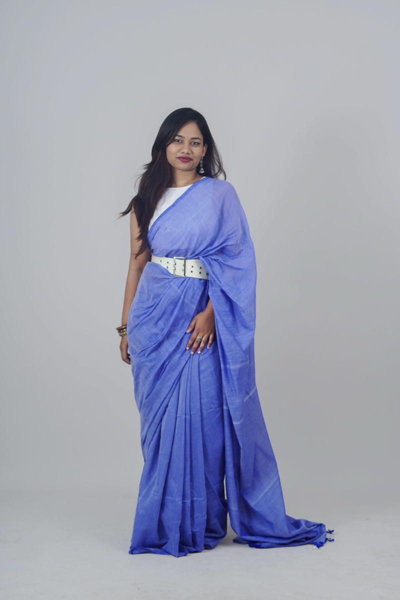 Woman wearing a blue saree with a white blouse against a gray background
