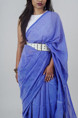 Woman wearing a blue saree with a white belt on a gray background
