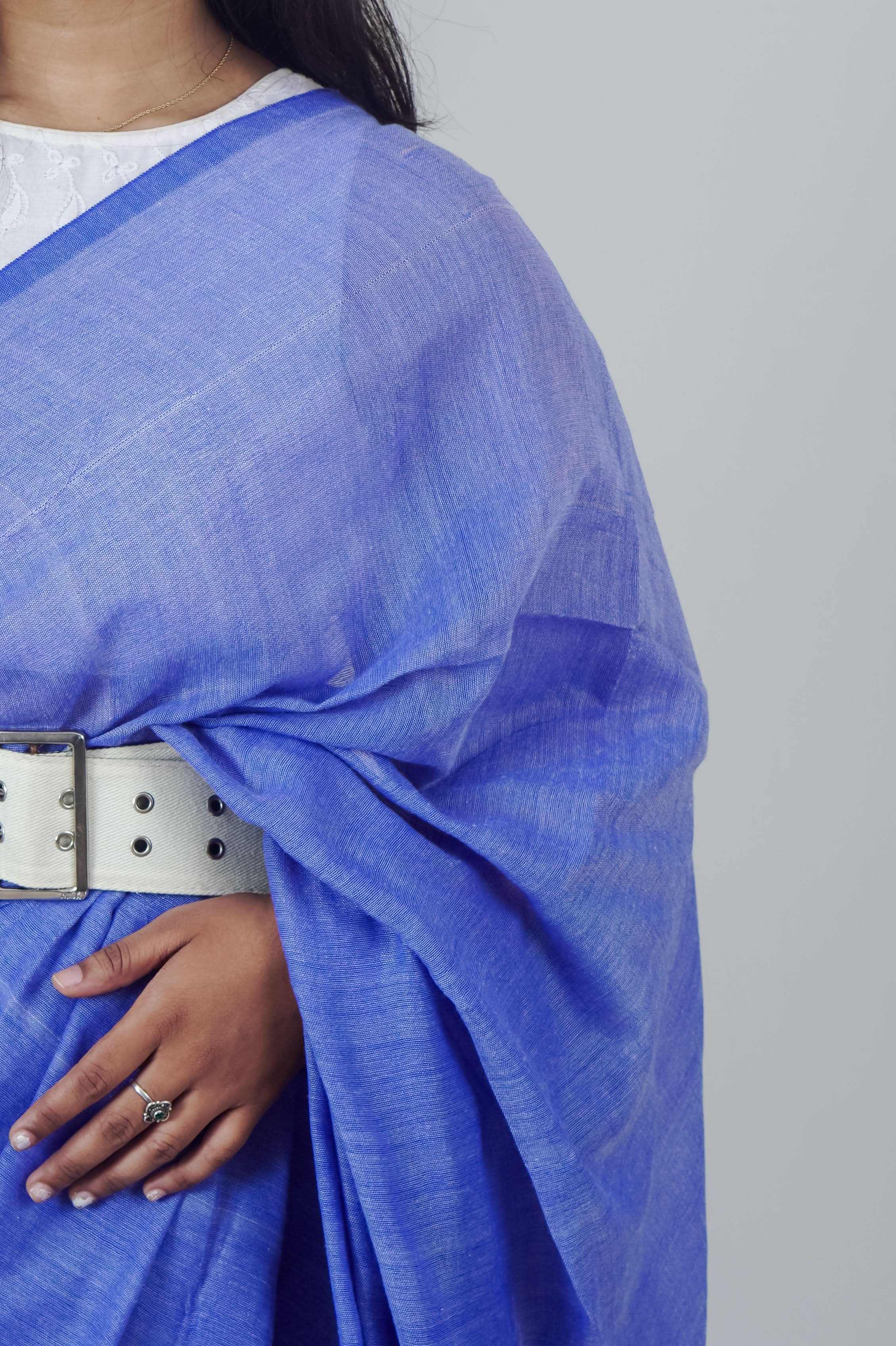 Blue fabric draped over a person with a white belt on a gray background