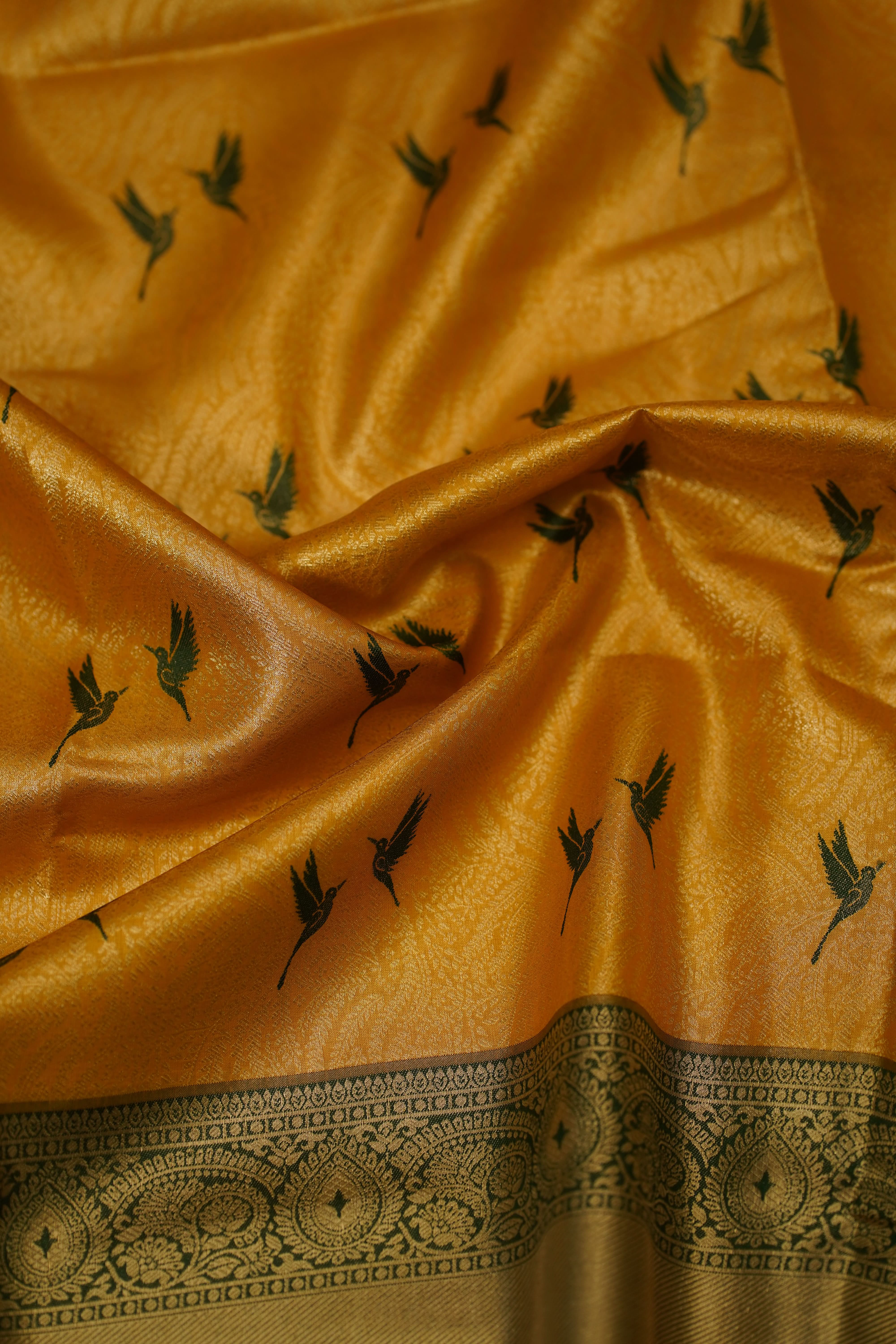 Close-up of a yellow fabric with black patterns and a decorative border.