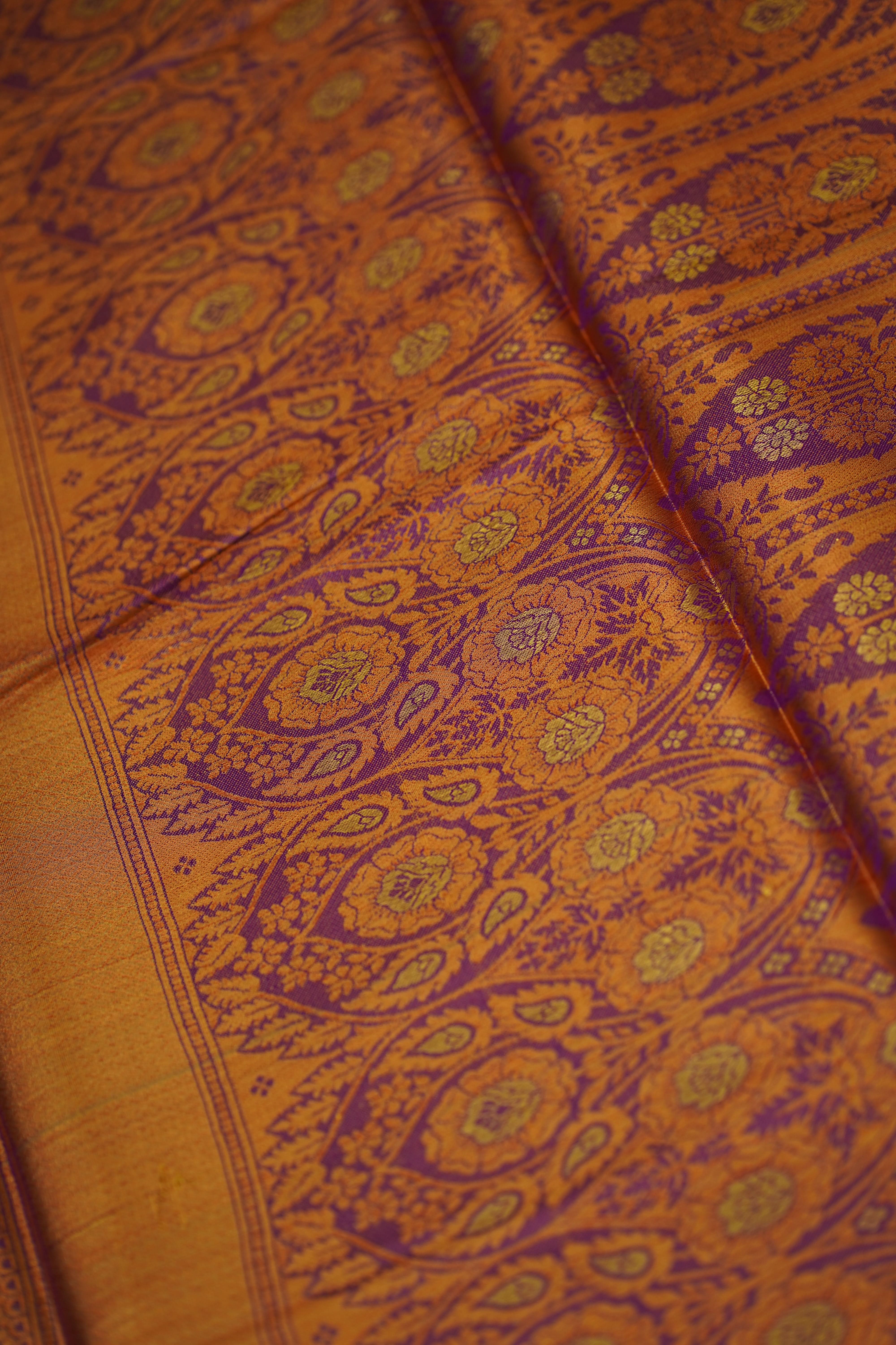Close-up of orange fabric with intricate purple and green patterns