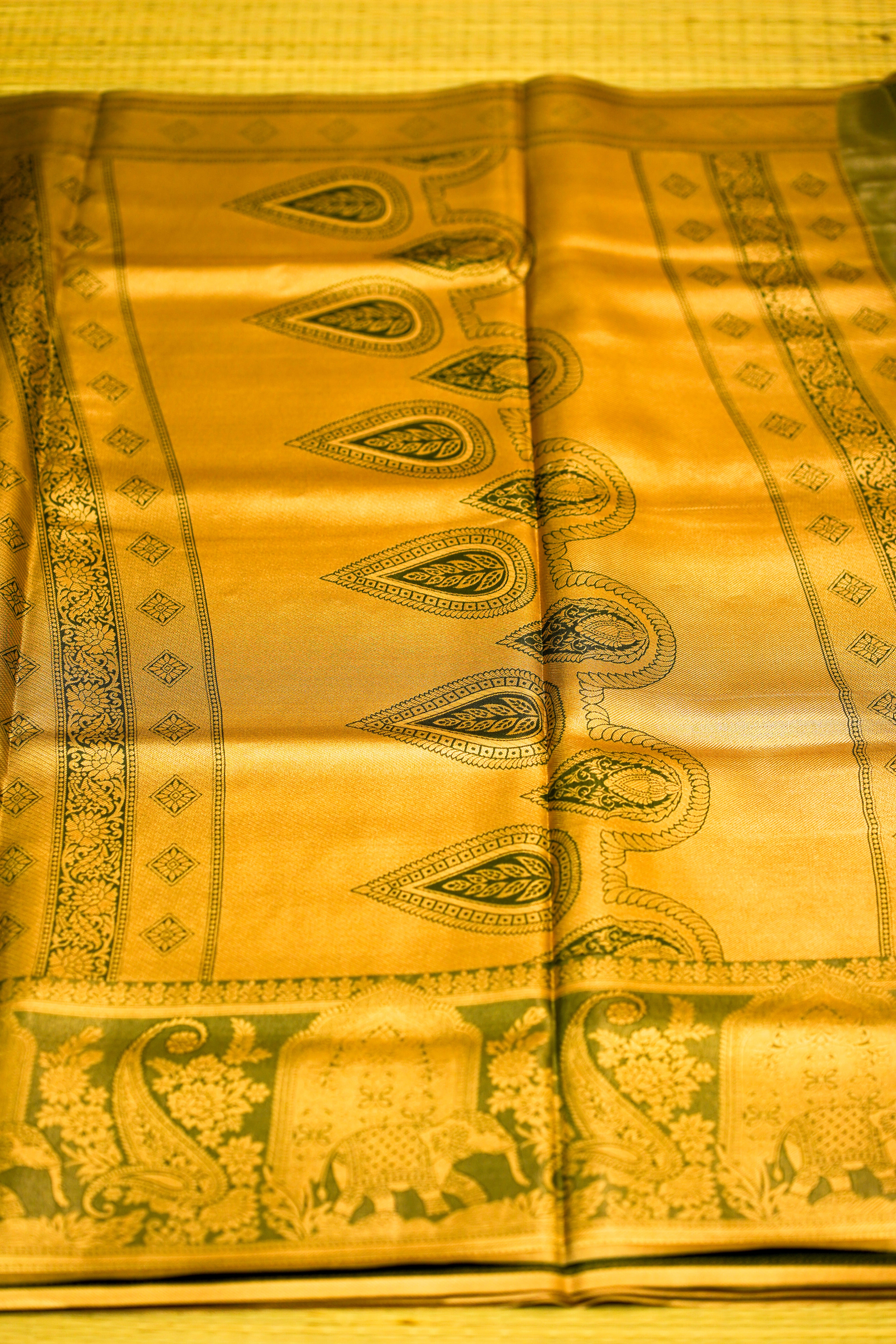 Yellow saree with green elephant and paisley patterns on a yellow background