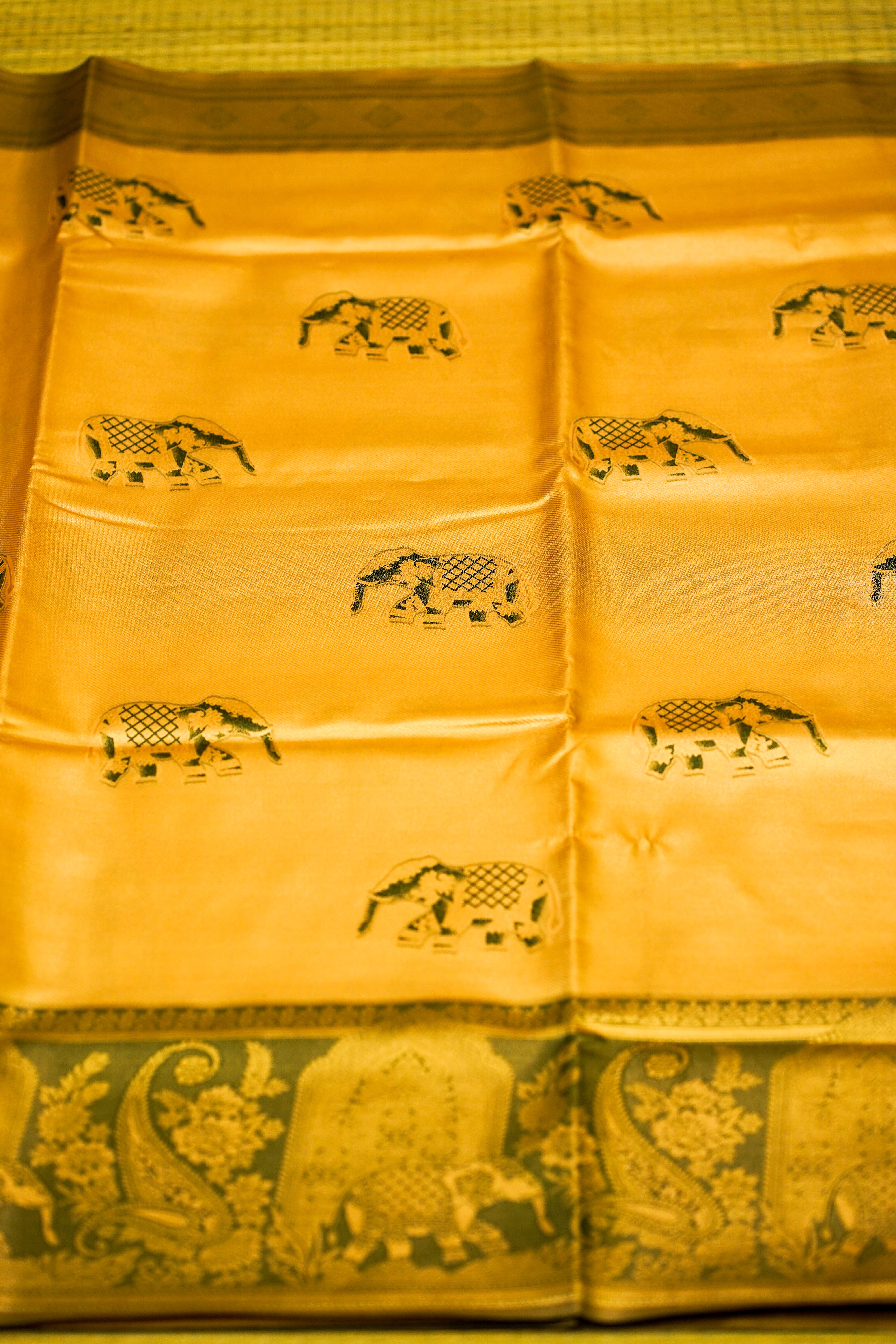 Yellow fabric with black elephant patterns on a green background