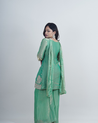 Woman wearing a green traditional outfit with a plain background www.laaki.co
