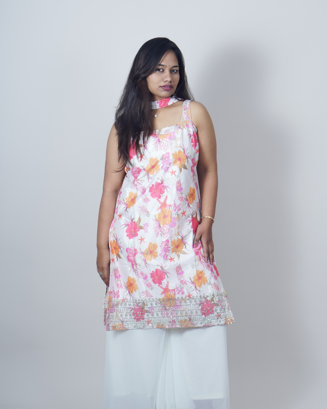 Woman wearing a floral sleeveless top with white pants on a plain background www.laaki.co