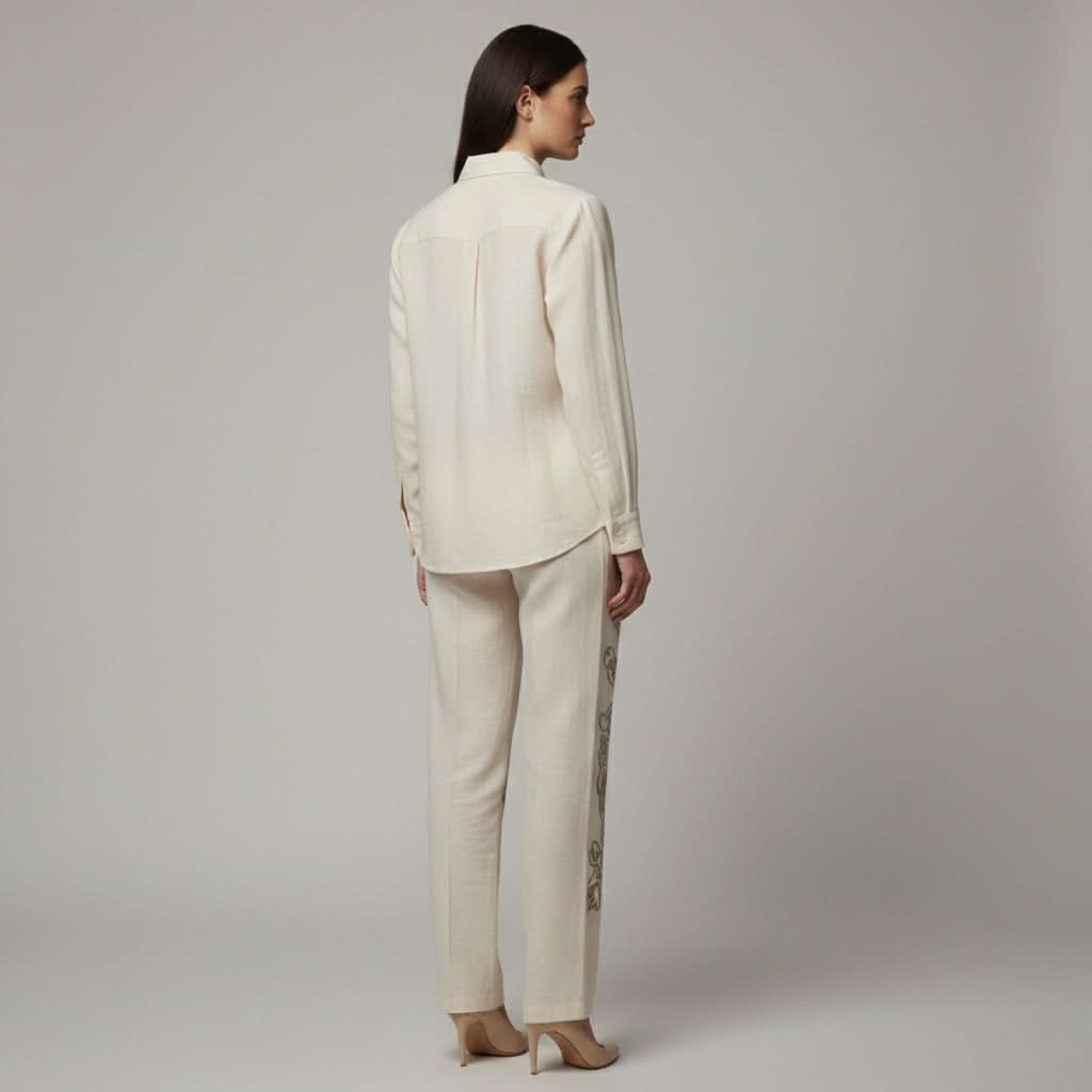 Woman wearing a cream-colored suit with a plain background. 