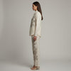 Woman wearing a cream-colored outfit with intricate black patterns on a plain background. www.laaki.co