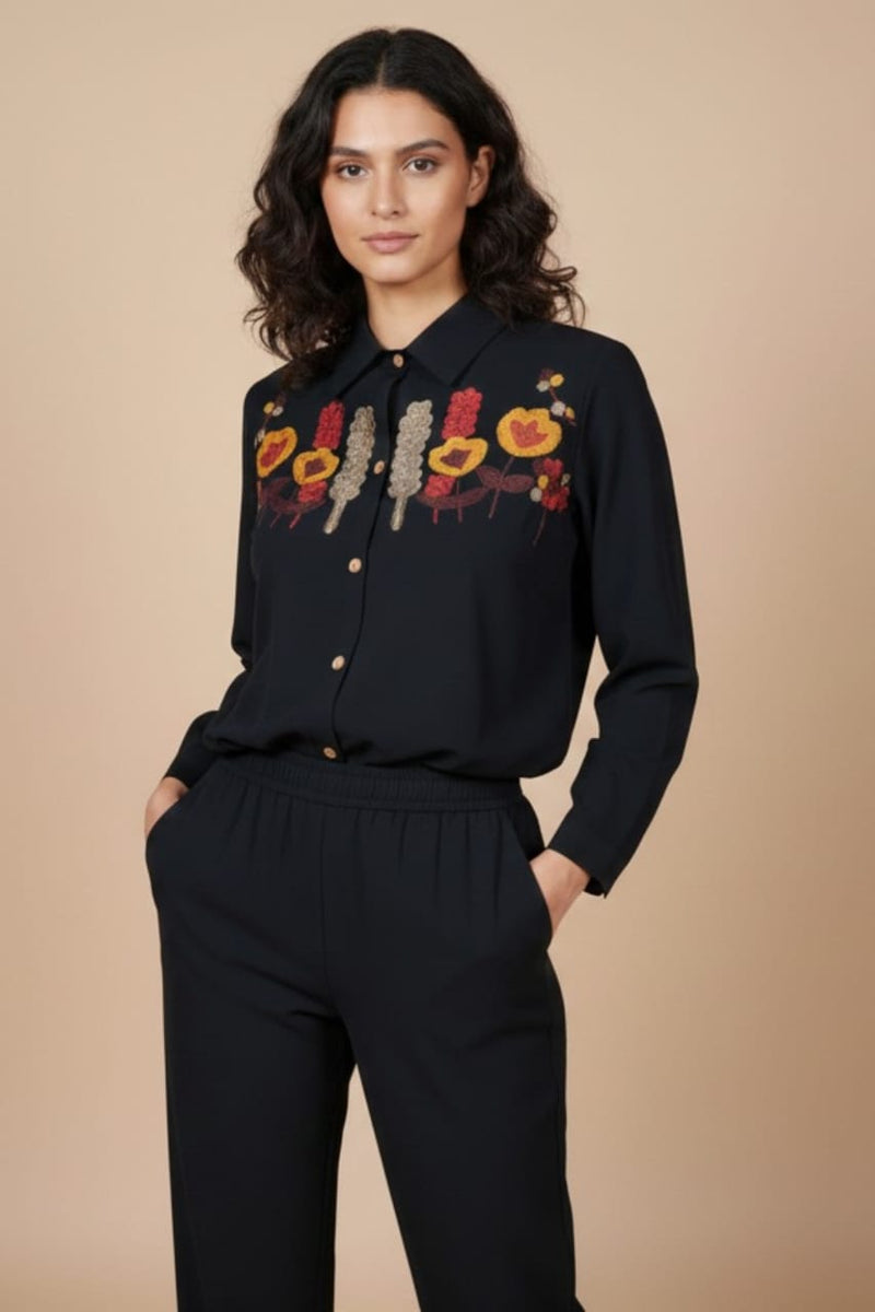 Woman wearing a black blouse with floral embroidery on a beige www.laaki.co background
