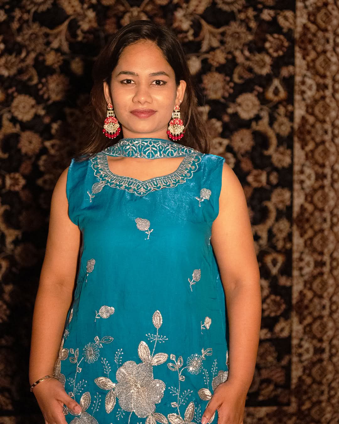 laaki Woman wearing a blue embroidered dress with a patterned background