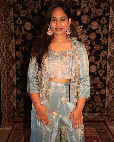 Woman wearing a floral outfit with a patterned background. laaki
