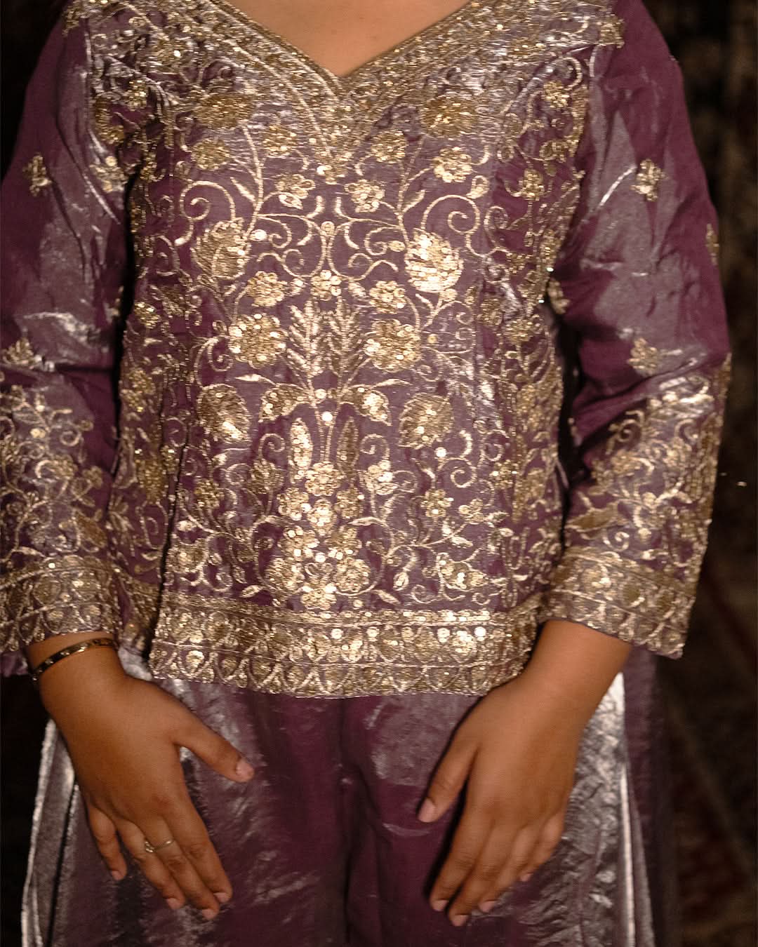 Purple traditional outfit with gold embroidery on a dark background laaki
