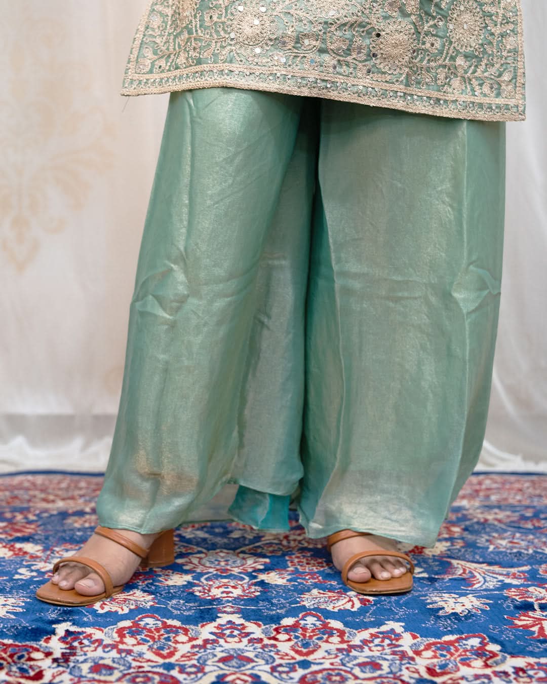 Light green traditional outfit with a patterned top on a decorative rug. laaki