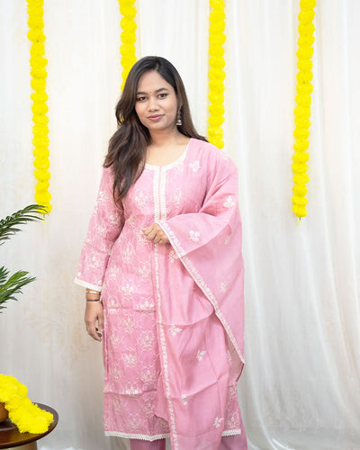 Woman wearing a pink traditional outfit with a white background and yellow decorations. laaki