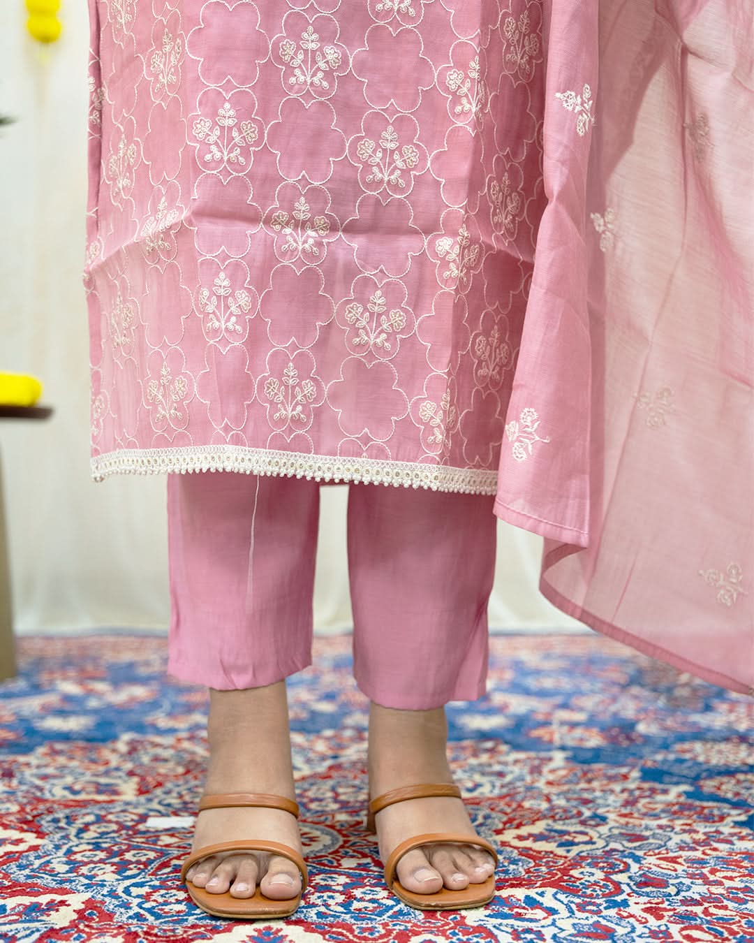Pink embroidered traditional outfit on a patterned rug. laaki
