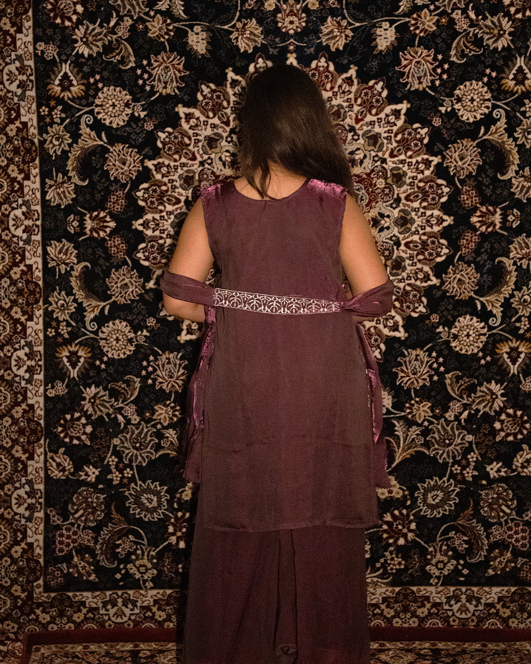 Person wearing a maroon traditional outfit with a patterned background