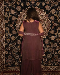 Person wearing a maroon traditional outfit with a patterned background