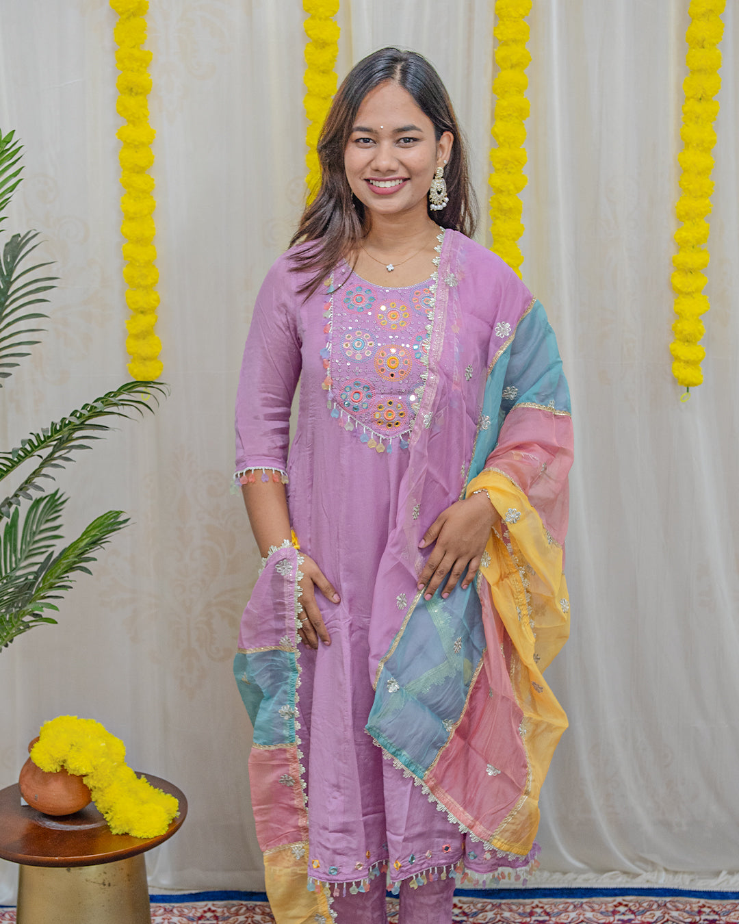 laaki Woman in a pink traditional outfit with colorful accents against a decorative background