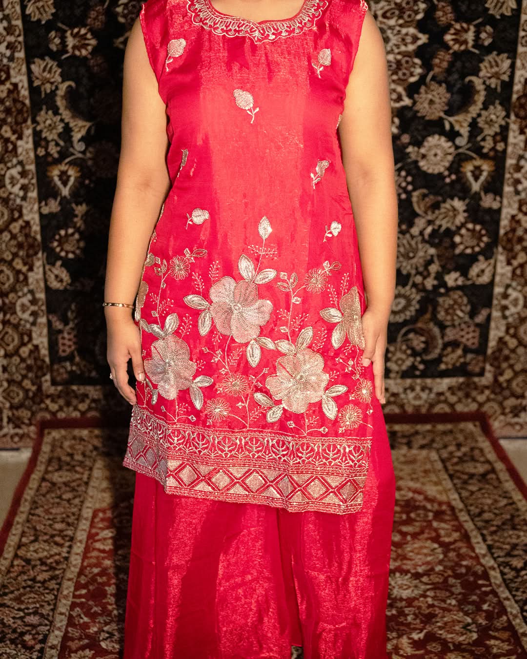 Red floral embroidered dress on a patterned carpet. laaki