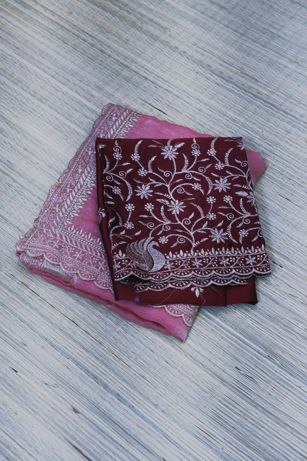 Two fabric items, one pink with lace details and one maroon with white floral patterns, on a textured surface.