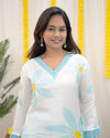 Woman wearing a white top with blue floral patterns against a yellow and white decorative background www.laaki.co