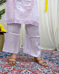 Person wearing a light purple outfit with floral embroidery on a patterned rug. www.laaki.co