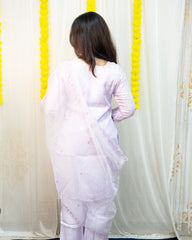 Woman wearing a white traditional outfit with a yellow and white decorative curtain in the background. www.laaki.co